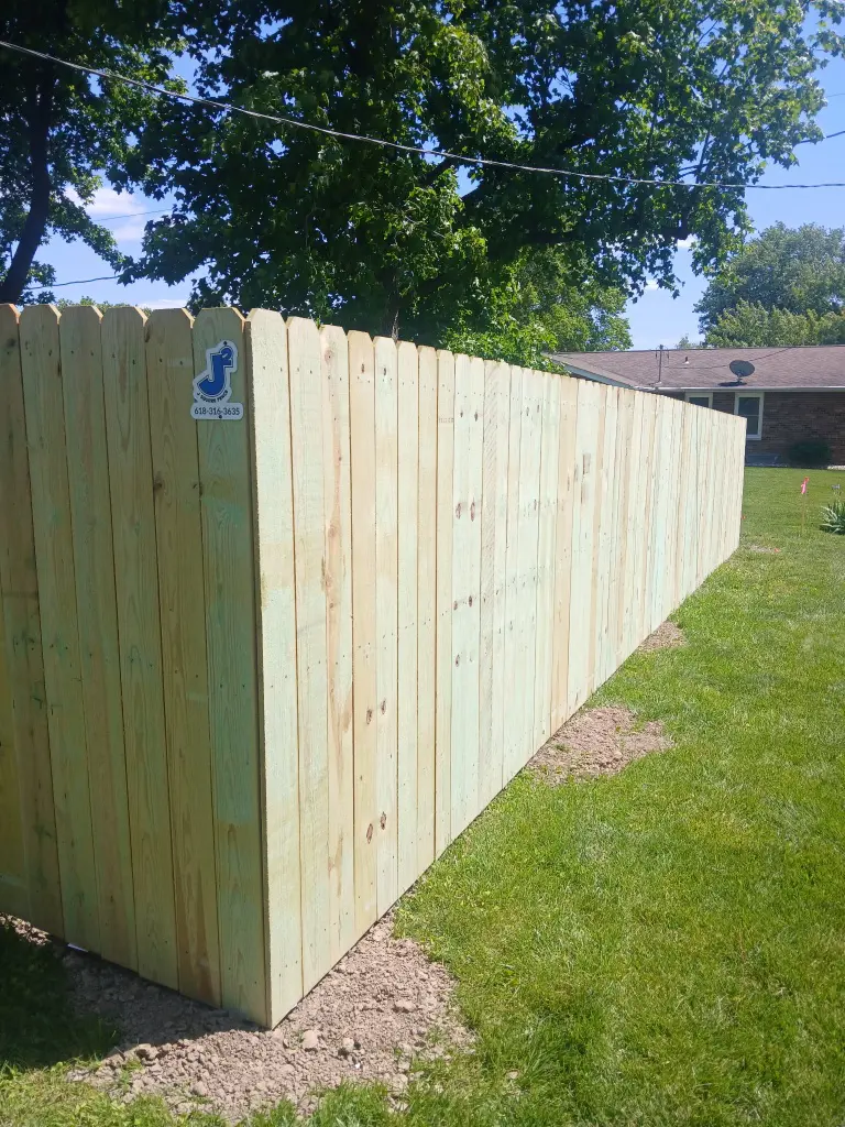 New wood privacy fence turning a corner beside a lawn.